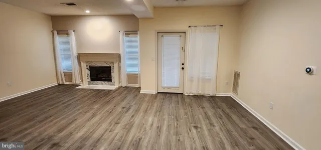 a view of an empty room with wooden floor and a fireplace