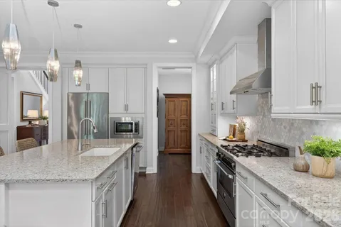 a kitchen with granite countertop kitchen island stainless steel appliances a sink stove and refrigerator