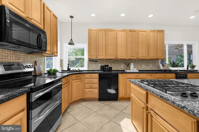 a kitchen with granite countertop a stove a sink a dining table and chairs