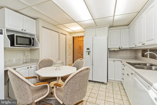 a kitchen with stainless steel appliances granite countertop a sink a stove a refrigerator with white cabinets and wooden floor