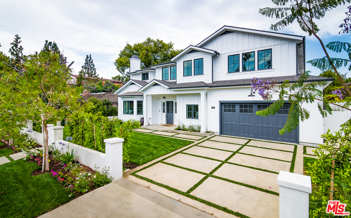 a front view of a house with a yard and potted plants