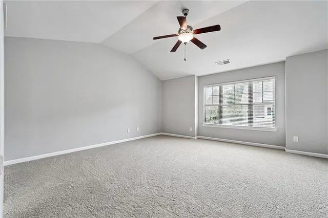 an empty room with windows and ceiling fan