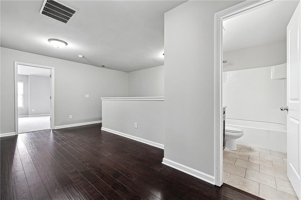 5590 Bright Cross Way Suwanee, GA 30024 - Photo 9 of 17 an empty room with wooden floor and windows