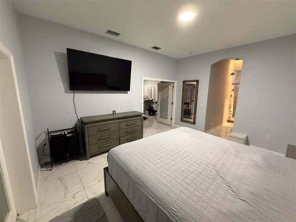 5690 Merlin Way St. Cloud, FL 34772 - Photo 18 of 46 a large bedroom with a bed and a flat screen tv