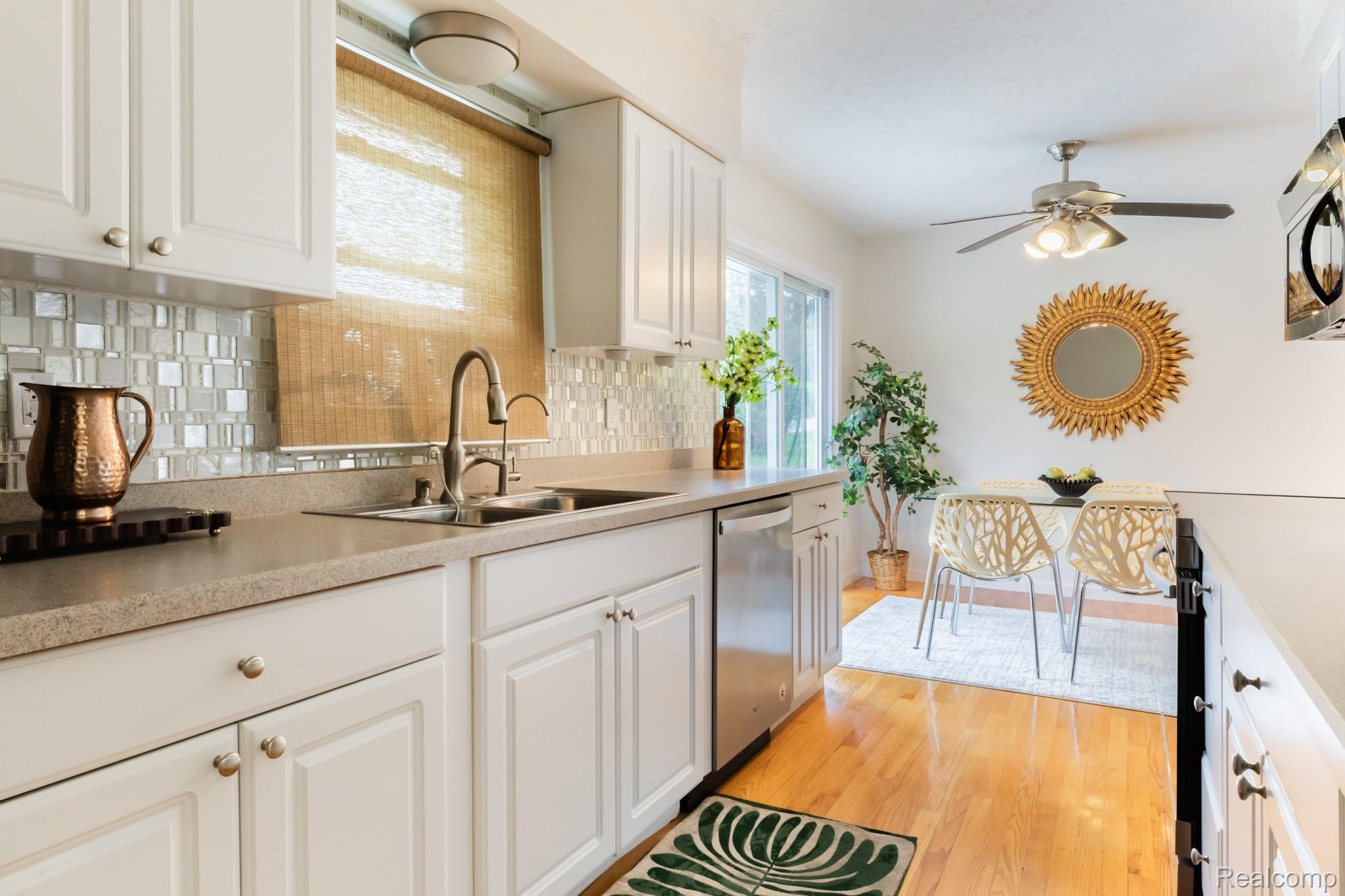 3882 Okemos Road Okemos, MI 48864 - Photo 18 of 50 White cabinetry with satin nickel hardware, stainless steel sink, mosaic tile backsplash, and light-toned countertops