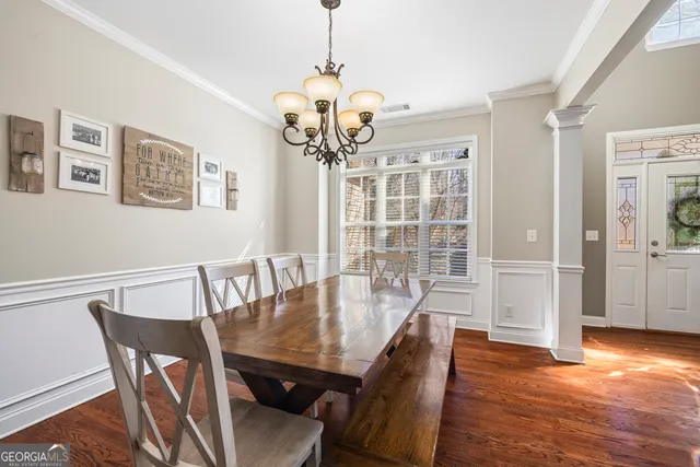 a kitchen with stainless steel appliances kitchen island granite countertop a refrigerator a stove a sink a dining table and chairs with wooden floor