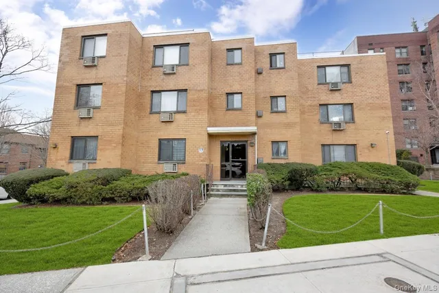 a front view of a brick building next to a yard
