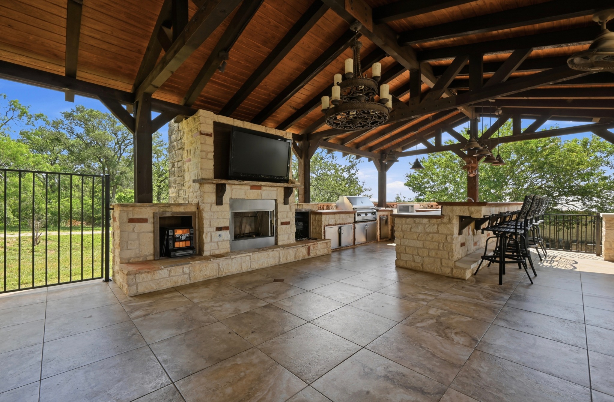 1175 Southern Way Luling, TX 78648 - Photo 6 of 40 An inviting outdoor living space features an impressive stone fireplace and full kitchen under a soaring wooden ceiling.