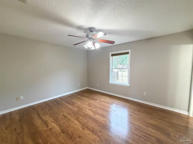 a view of an empty room with window and chandelier fan