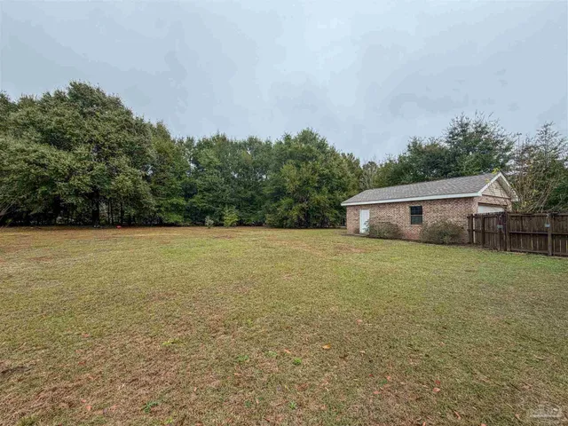 a front view of house with yard and trees in the background