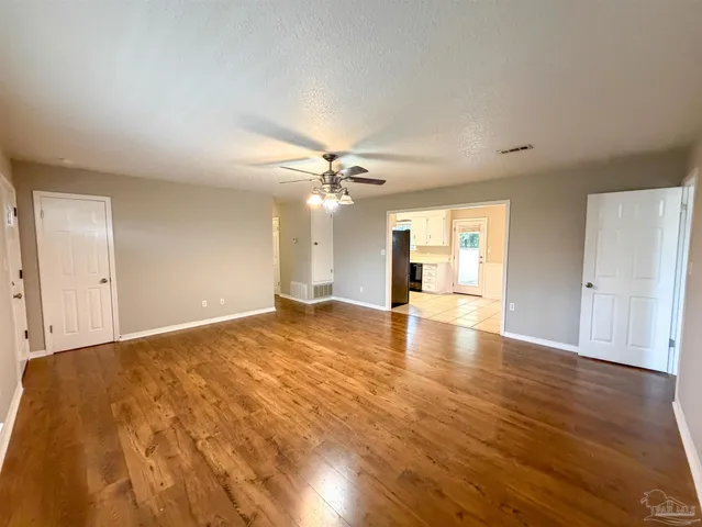 a view of empty room with wooden floor and fan