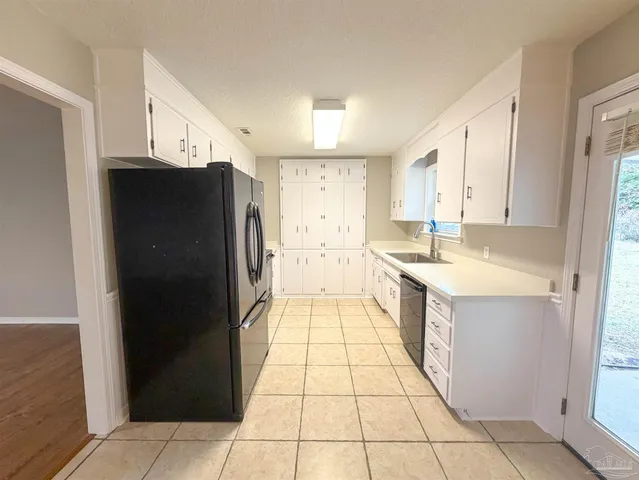 a large white kitchen with a sink and refrigerator