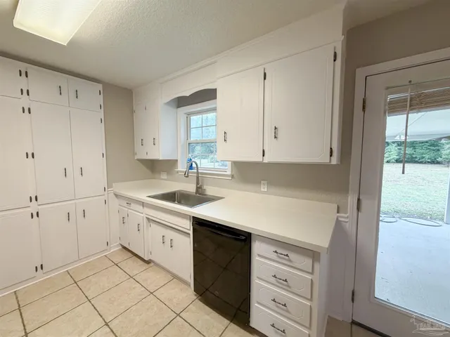 a kitchen with white cabinets appliances and a window