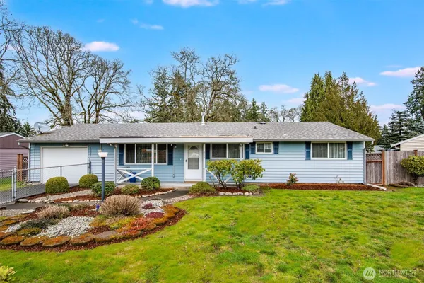 a front view of a house with garden and trees