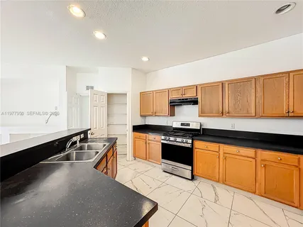 a large kitchen with granite countertop a stove sink and cabinets