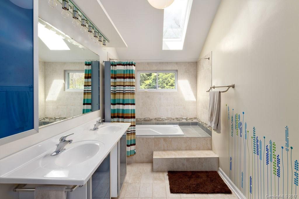 93 School Road Asheville, NC 28806 - Photo 10 of 24 a bathroom with a double vanity sink a mirror and a bathtub