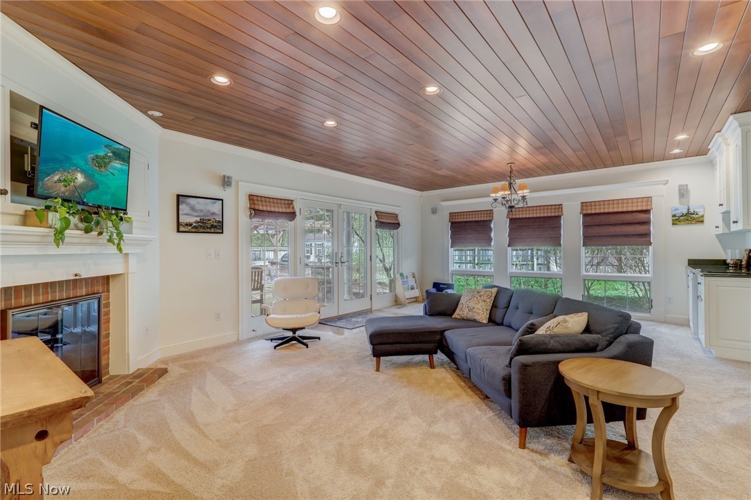 102 Wolcott Road Akron, OH 44313 - Photo 13 of 48 Carpeted living room featuring french doors, wood ceiling, a brick fireplace, ornamental molding, and a chandelier