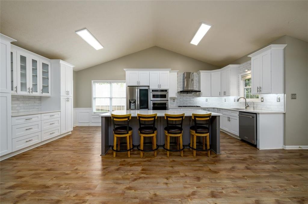 6391 Compass Drive Flowery Branch, GA 30542 - Photo 1 of 1 a kitchen with stainless steel appliances granite countertop a stove top oven a sink a dining table and chairs with wooden floor