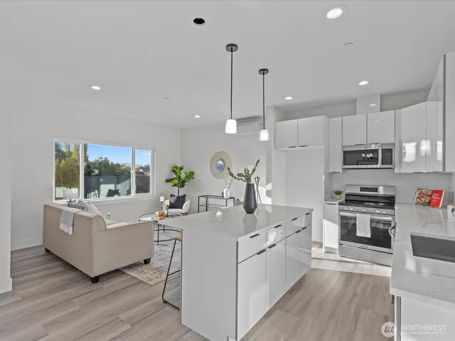 a large white kitchen with kitchen island a large counter top space a sink stainless steel appliances and cabinets