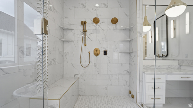 1682 North 1950 W Street, Unit 9 Provo, UT 84604 - Photo 32 of 84 Walk-in shower with full height stone-look tile, hexagonal floor tile, built-in bench with gold-tone trim, and built-in shelving