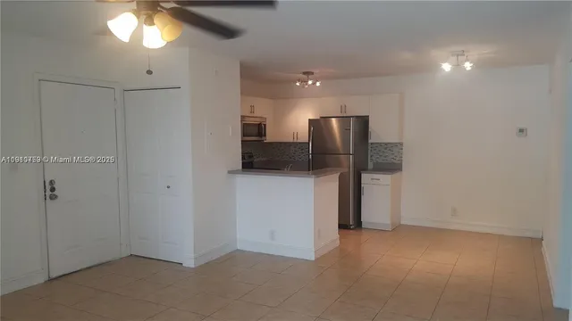 a view of a refrigerator in kitchen and a chandelier fan
