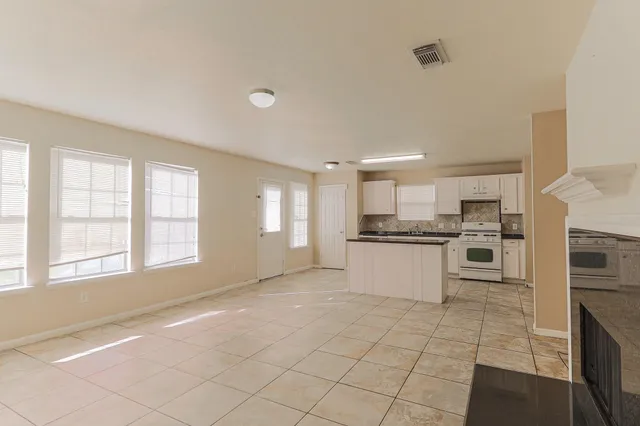 a large white kitchen with a stove a sink dishwasher and a refrigerator with white cabinets