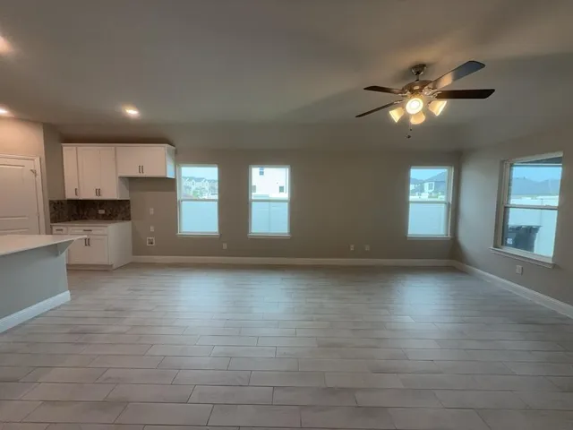 a view of empty room with kitchen and window
