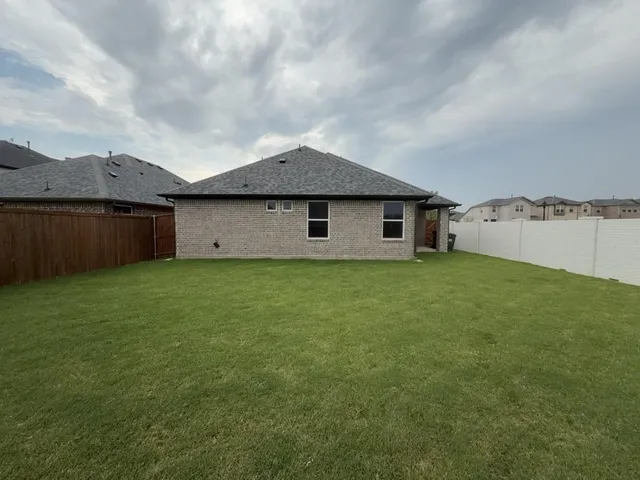 a view of a green field with house in the background