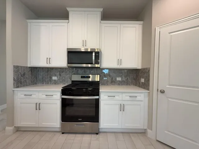 a kitchen with white cabinets and stainless steel appliances