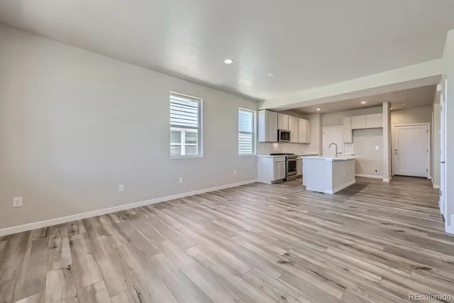 a view of empty room with wooden floor and window