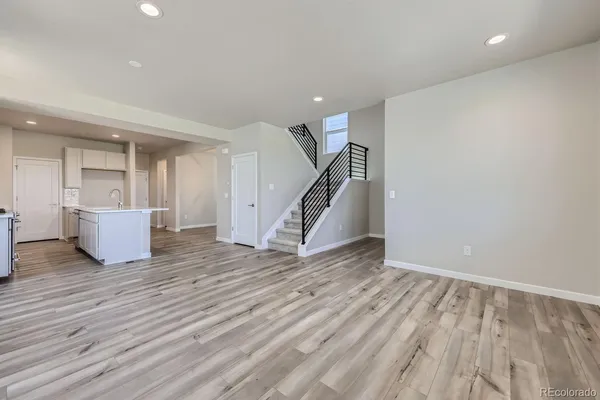 a view of an empty room with wooden floor and a ceiling fan