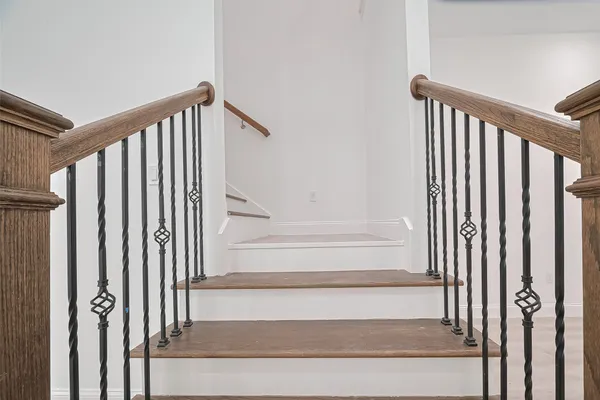 a view of staircase with railing and white walls