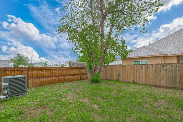 a view of a backyard with a tree and wooden fence