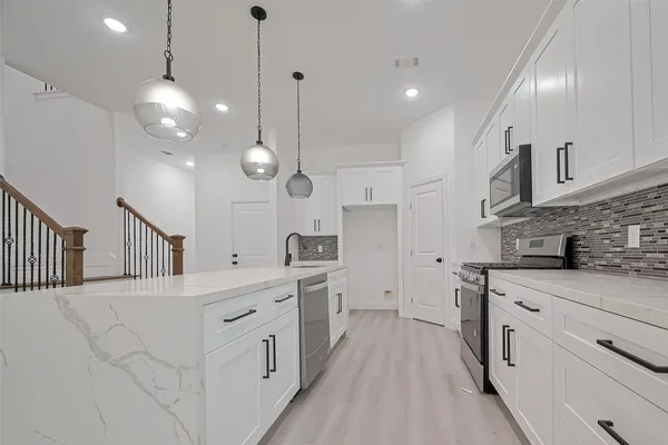 a kitchen with white cabinets and appliances