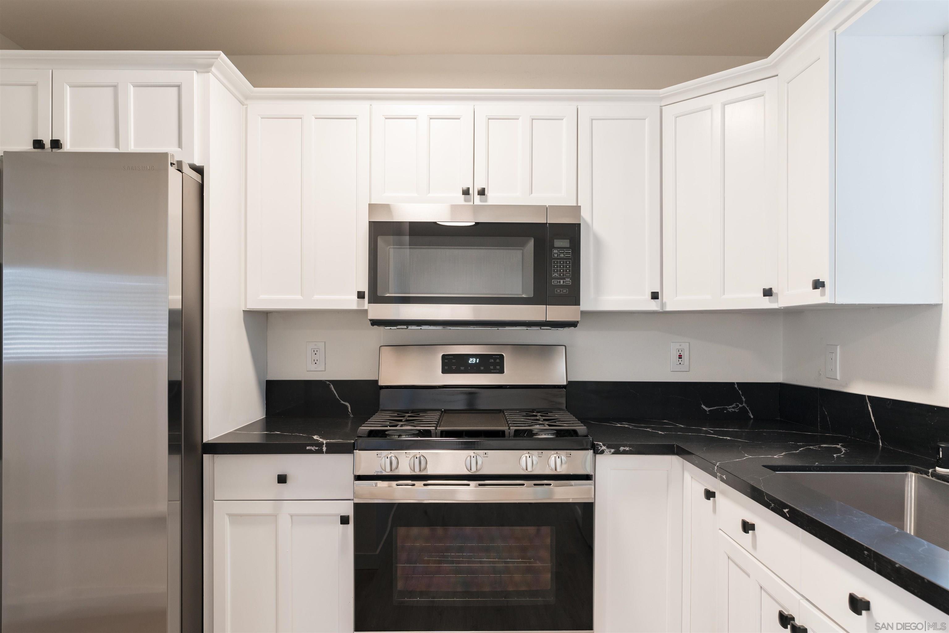 a kitchen with granite countertop white cabinets and stainless steel appliances