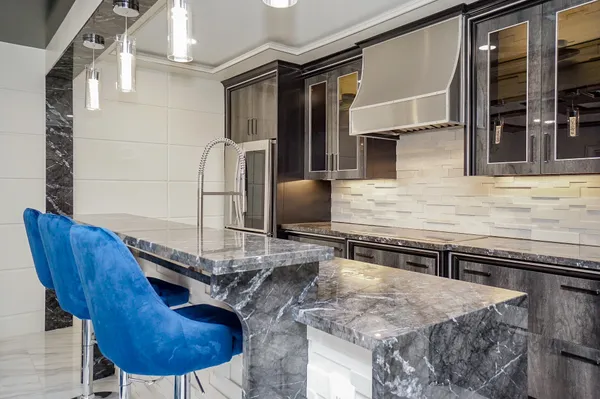 a kitchen with stainless steel appliances kitchen island granite countertop a sink and a black white refrigerator