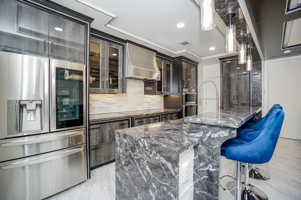 a kitchen with stainless steel appliances kitchen island granite countertop a refrigerator and cabinets