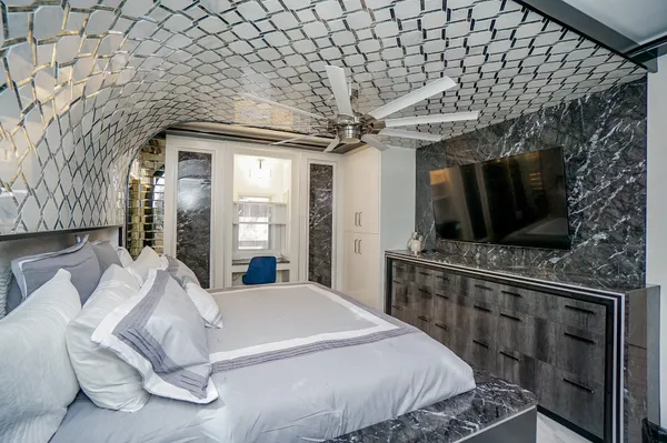 a spacious bedroom with a bed a flat tv screen and a dresser