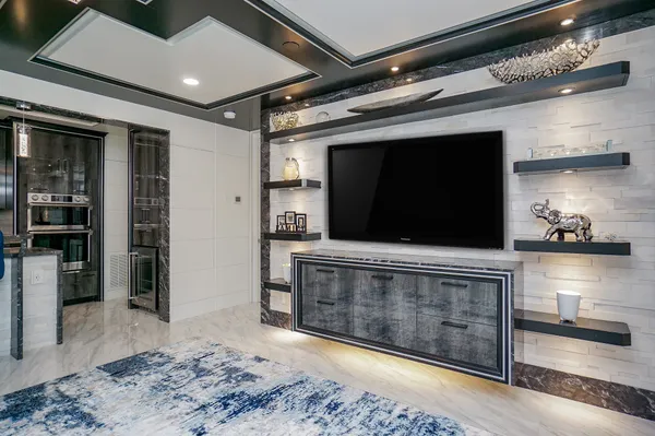 a living room with stainless steel appliances kitchen island granite countertop a tv and a wooden floor