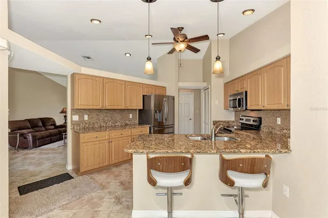a kitchen with stainless steel appliances granite countertop a refrigerator a stove and a sink