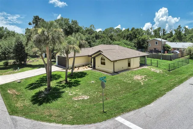 a aerial view of a house with a big yard potted plants and large tree
