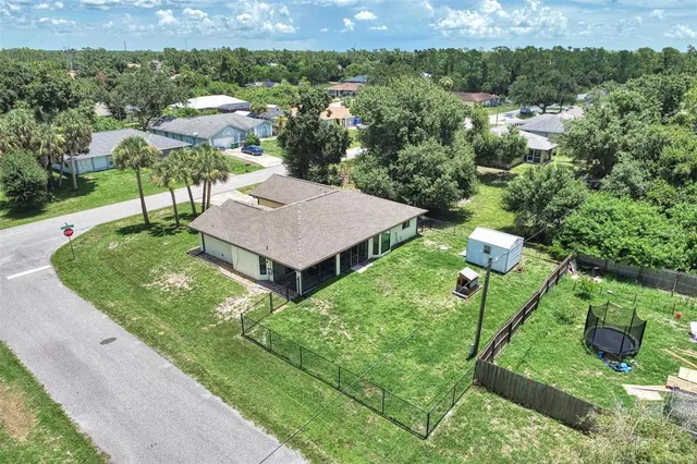 an aerial view of residential houses with outdoor space and trees