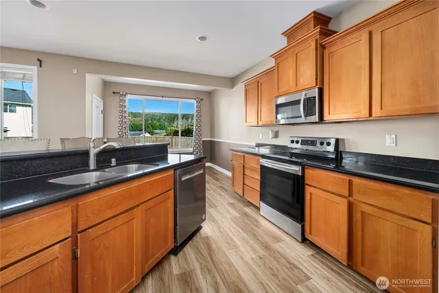 a kitchen with stainless steel appliances granite countertop wooden cabinets a sink and a stove