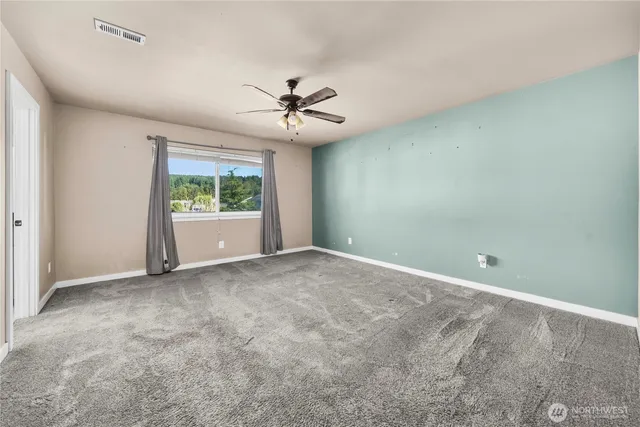 an empty room with windows and ceiling fan