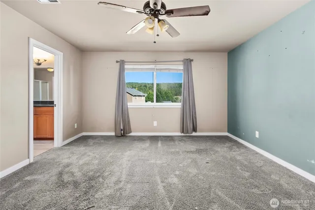 an empty room with chandelier fan and windows