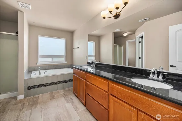 a bathroom with a granite countertop bathtub a sink and a mirror