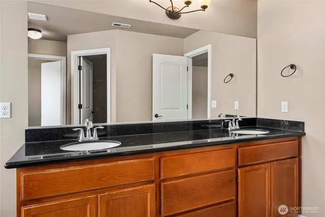 a bathroom with granite countertop double vanity and a mirror