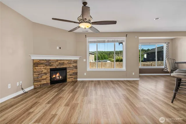a view of an empty room with wooden floor fireplace and a window