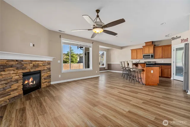 a view of a kitchen with furniture a ceiling fan and wooden floor