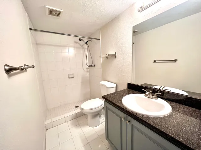 a bathroom with a granite countertop sink toilet and shower